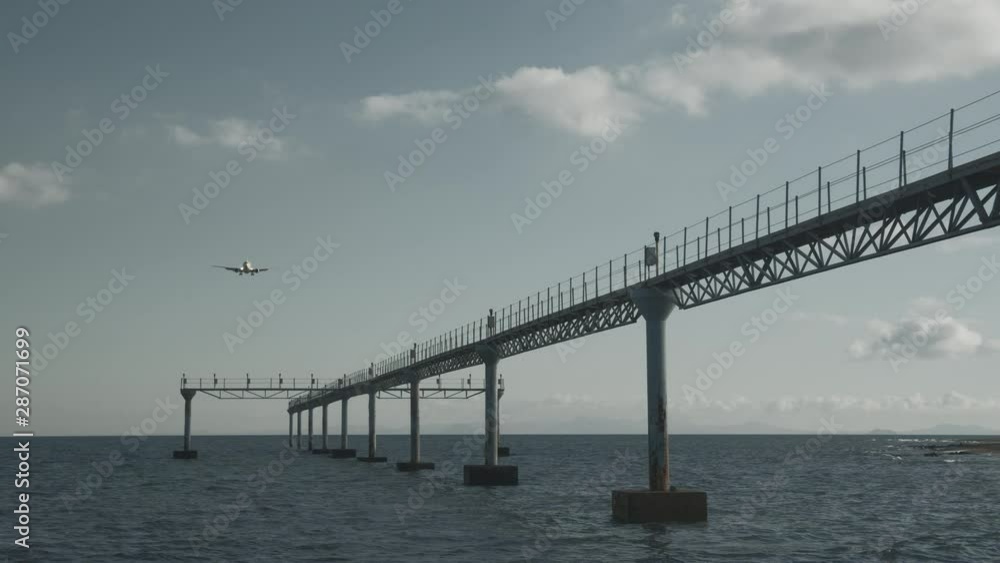 An aircraft goes down, flying along a runway construction, built in a sea An aircraft goes down, flying along a runway construction, built in a sea