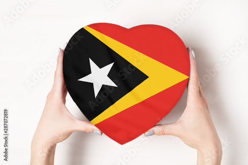Flag of East Timor on a heart shaped box in a female hands. White background
