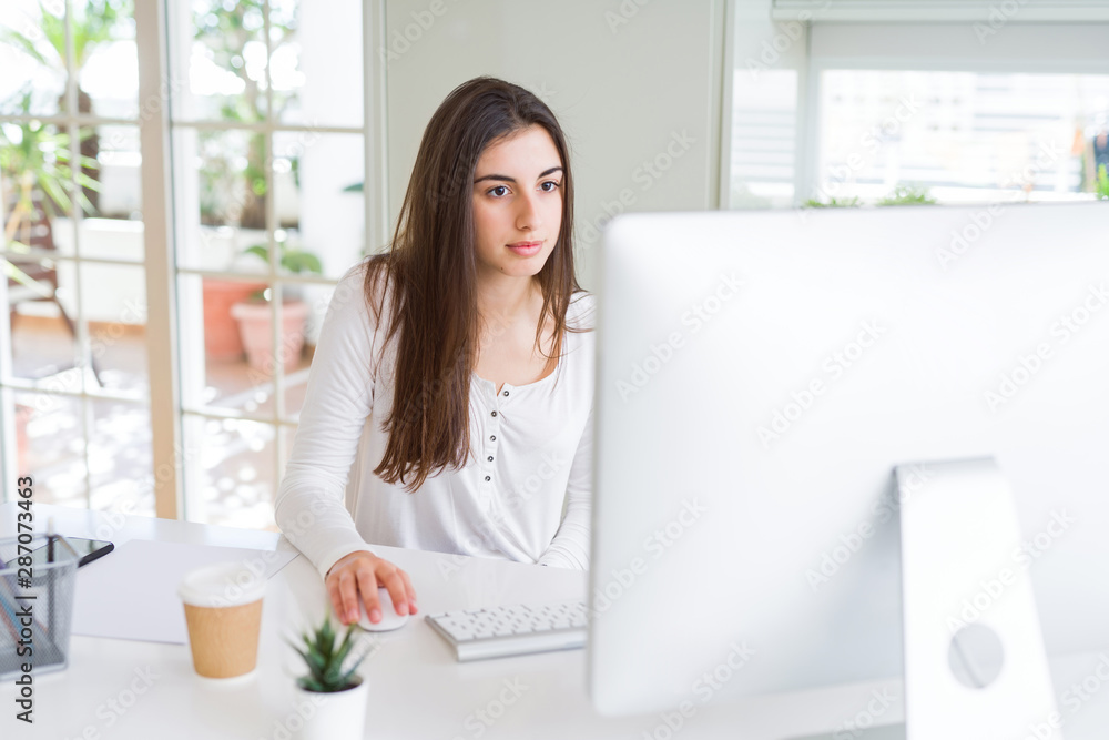 Beautiful young business woman working using computer, smiling and concentrated on online work Beautiful young business woman working using computer, smiling and concentrated on online work