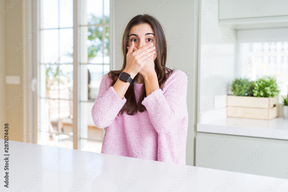 Beautiful young woman wearing pink sweater shocked covering mouth with hands for mistake. Secret concept. Beautiful young woman wearing pink sweater shocked covering mouth with hands for mistake. Secret concept.