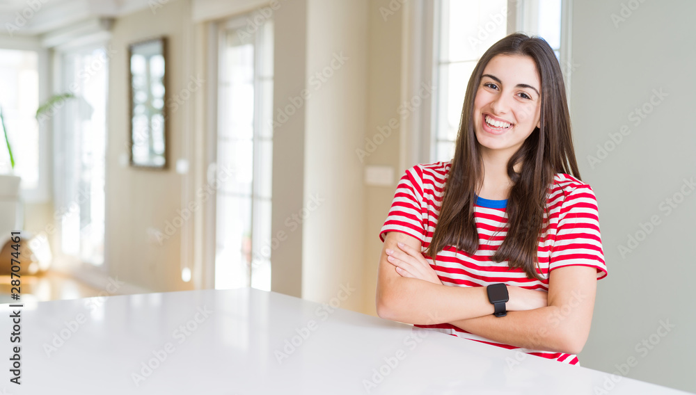 Beautiful young woman wearing casual stripes t-shirt happy face smiling with crossed arms looking at the camera. Positive person. Beautiful young woman wearing casual stripes t-shirt happy face smiling with crossed arms looking at the camera. Positive person.
