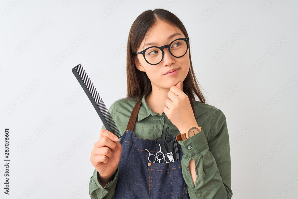 Chinese hairdresser woman wearing glasses holding comb over isolated white background serious face thinking about question, very confused idea Chinese hairdresser woman wearing glasses holding comb over isolated white background serious face thinking about question, very confused idea