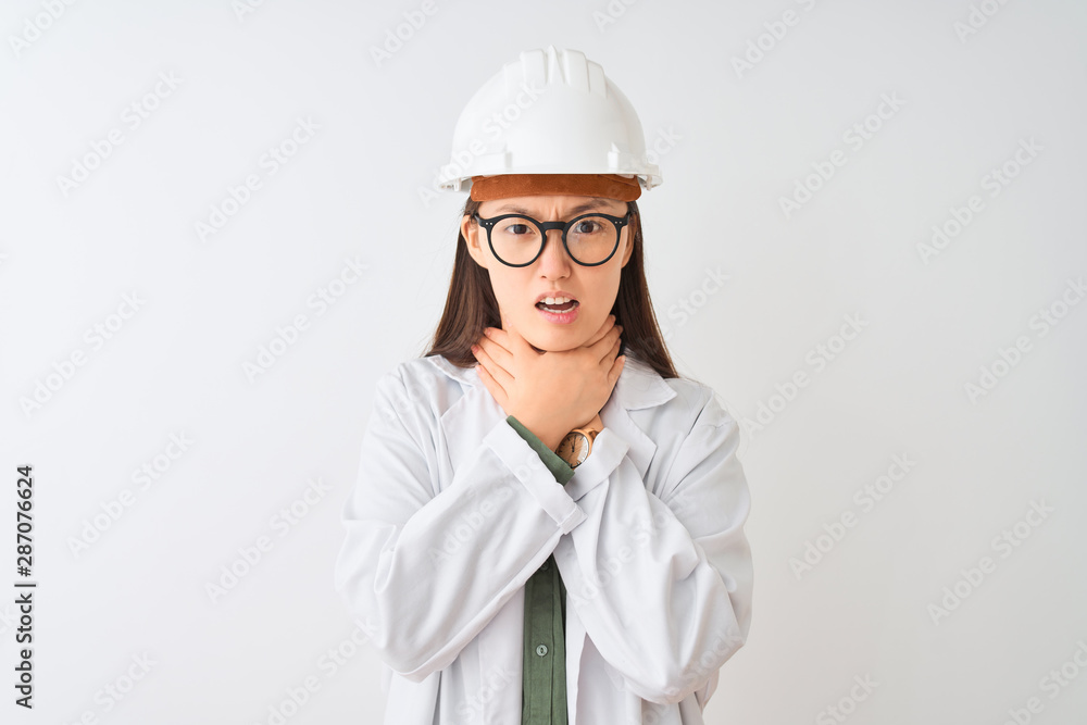 Young chinese engineer woman wearing coat helmet glasses over isolated white background shouting and suffocate because painful strangle. Health problem. Asphyxiate and suicide concept. Young chinese engineer woman wearing coat helmet glasses over isolated white background shouting and suffocate because painful strangle. Health problem. Asphyxiate and suicide concept.