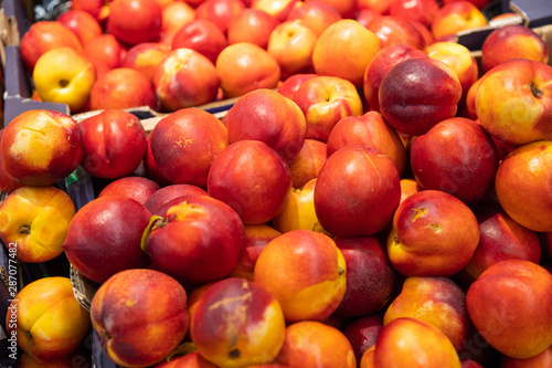 Colourful delicious freshly-harvested nectarine in paper boxes at farmer's market of grocery store. For agruculture, food illustration background