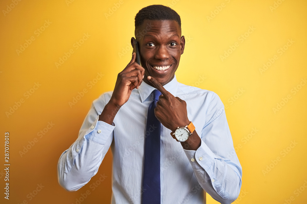African american businessman talking on smartphone standing over isolated yellow background very happy pointing with hand and finger African american businessman talking on smartphone standing over isolated yellow background very happy pointing with hand and finger