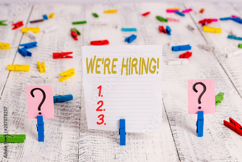 Text sign showing We Are Re Hiring. Business photo showcasing process of reviewing applications and finding candidates Scribbled and crumbling sheet with paper clips placed on the wooden table