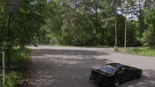 Black car drifting on road turn in countryside front aerial view. Racing car driving with driftage on asphalt. Old car turning with drift. Japanese rear wheel drive car photo