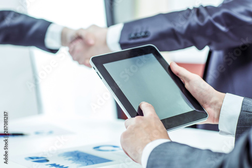 businessman with digital tablet on background of business partners handshaking
