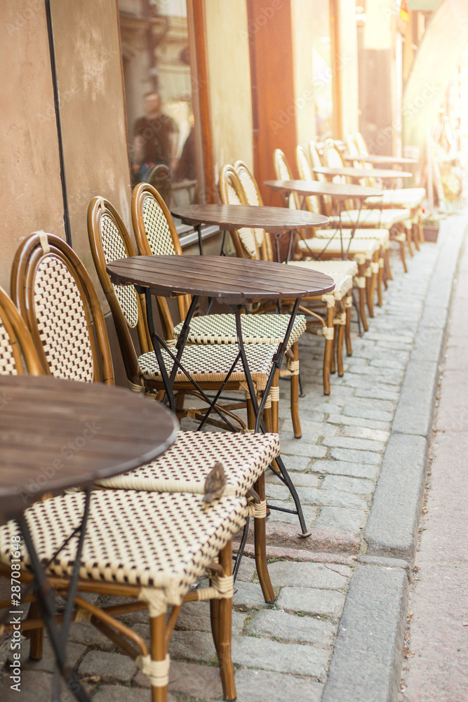 Empty tables in between dining hours. Old fashioned cafe terrace in a summer day