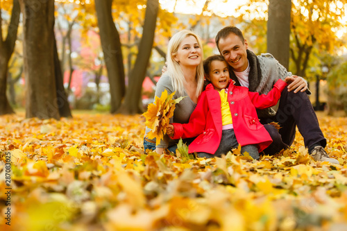 Happy family is sitting in beautiful autumn park