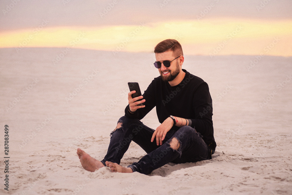 Young man using smart phone in the desert . Freelancer on vacation