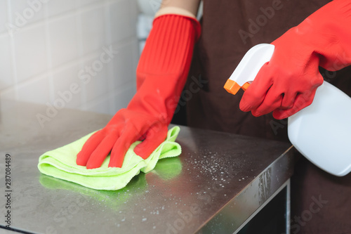 house maid cleaning sink in the kitchen with sponge and cleanser. photo