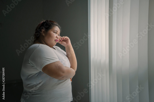 Canvastavla Pensive obese woman looking out the window