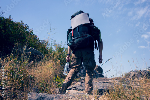 hiker in a backpack rises in the mountains