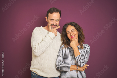 Beautiful middle age couple wearing winter sweater over isolated purple background looking confident at the camera with smile with crossed arms and hand raised on chin. Thinking positive. © Krakenimages.com