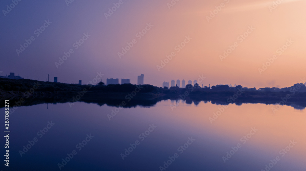 Skyscrapers and trees with reservoir at dusk time