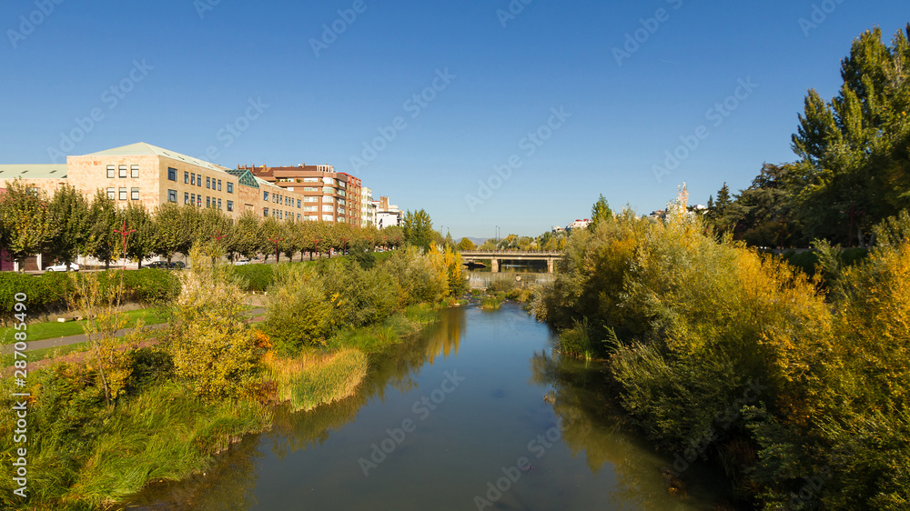 Bernesga River in autumn as it passes through the city of León with green areas, shrubs and groves on the banks. Spain