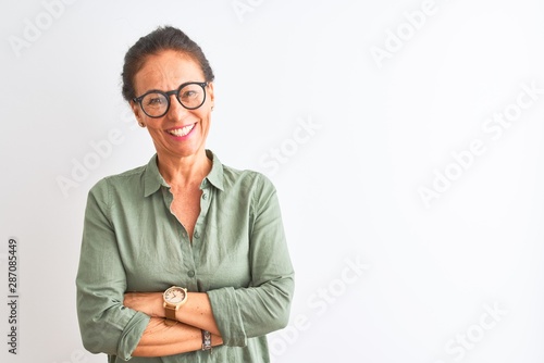 Middle age woman wearing green shirt and glasses standing over isolated white background happy face smiling with crossed arms looking at the camera. Positive person.