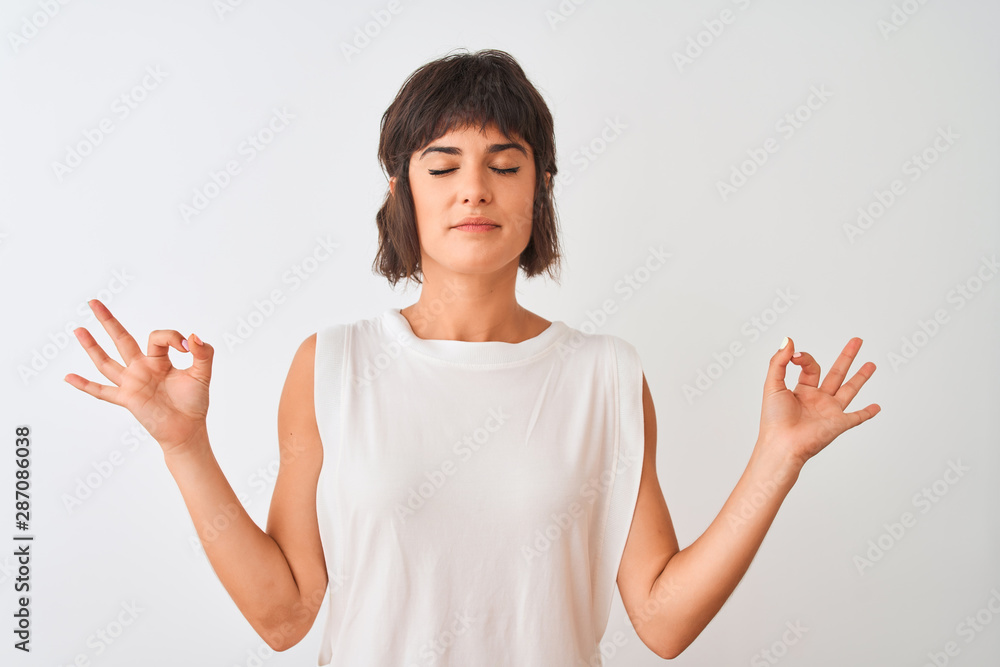 Young beautiful woman wearing casual t-shirt standing over isolated white background relax and smiling with eyes closed doing meditation gesture with fingers. Yoga concept. Young beautiful woman wearing casual t-shirt standing over isolated white background relax and smiling with eyes closed doing meditation gesture with fingers. Yoga concept.