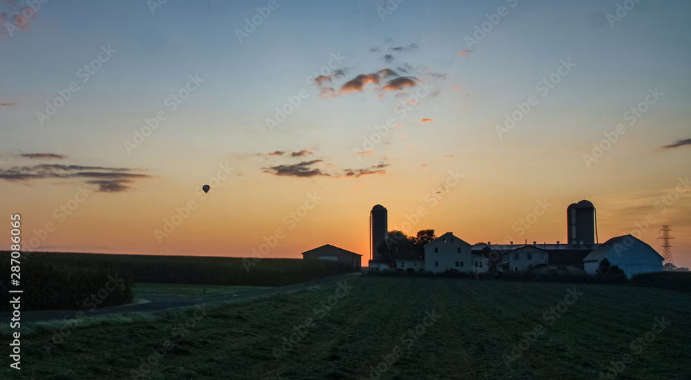 Fototapeta premium Sunrise Over an Amish Farm with Blues and Reds with Hot air Balloon