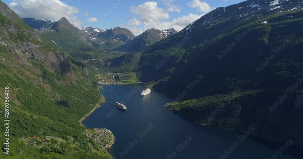 Aerial: Ships in Geirangerfjord amidst beautiful mountain range on sunny day during winter - Geiranger Fjord, Norway Aerial: Ships in Geirangerfjord amidst beautiful mountain range on sunny day during winter - Geiranger Fjord, Norway