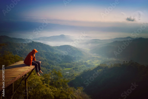 Young man sitting on the wooden bridge