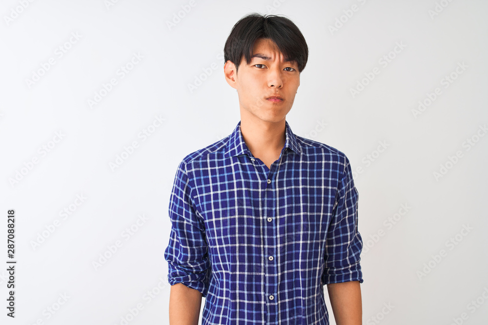 Young chinese man wearing casual blue shirt standing over isolated white background skeptic and nervous, frowning upset because of problem. Negative person.