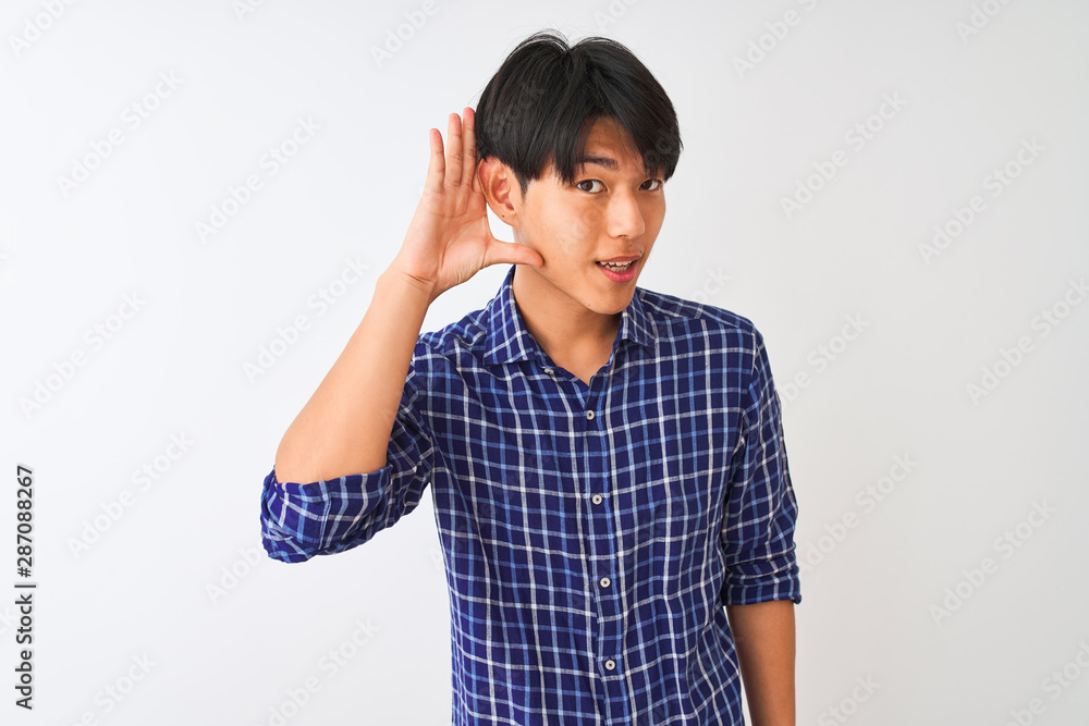 Young chinese man wearing casual blue shirt standing over isolated white background smiling with hand over ear listening an hearing to rumor or gossip. Deafness concept. Young chinese man wearing casual blue shirt standing over isolated white background smiling with hand over ear listening an hearing to rumor or gossip. Deafness concept.