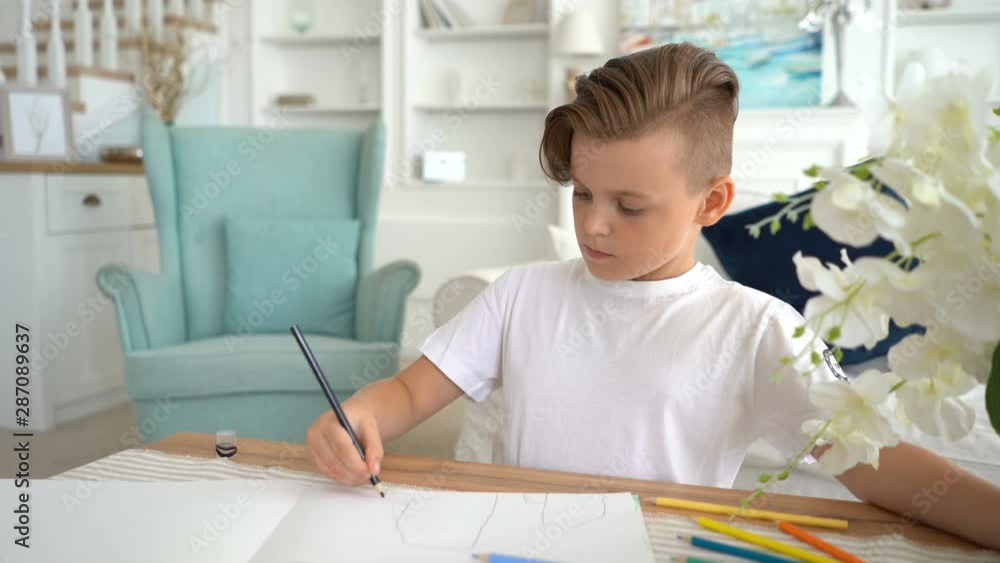 Little boy sitting at table and drawing with colored pencils Little boy sitting at table and drawing with colored pencils