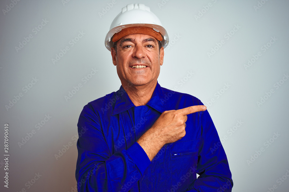Handsome middle age worker man wearing uniform and helmet over isolated white background with a big smile on face, pointing with hand and finger to the side looking at the camera. Handsome middle age worker man wearing uniform and helmet over isolated white background with a big smile on face, pointing with hand and finger to the side looking at the camera.