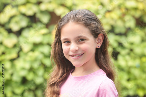 Close up Portrait of 8 Years Old Girl, with Brown Long Hair and Big Brown Eyes, Happy Child, Green Background  © Olga