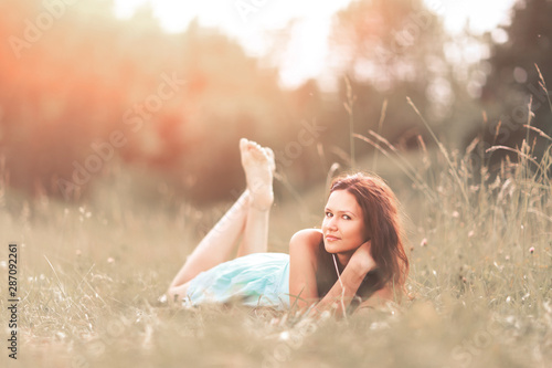 Beautiful young woman on grass in summer park