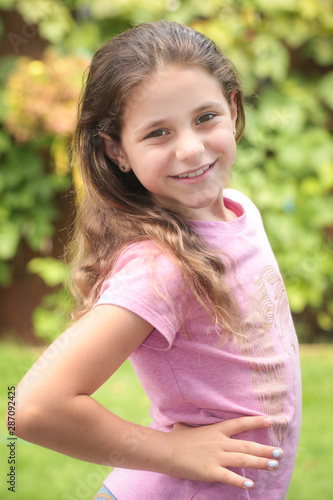 Close up Portrait of 8 Years Old Girl, with Brown Long Hair and Big Brown Eyes, Happy Child, Green Background 