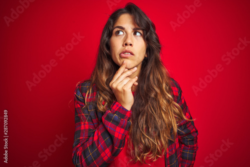 Young beautiful woman wearing casual jacket standing over red isolated background smiling cheerful showing and pointing with fingers teeth and mouth. Dental health concept. © Krakenimages.com