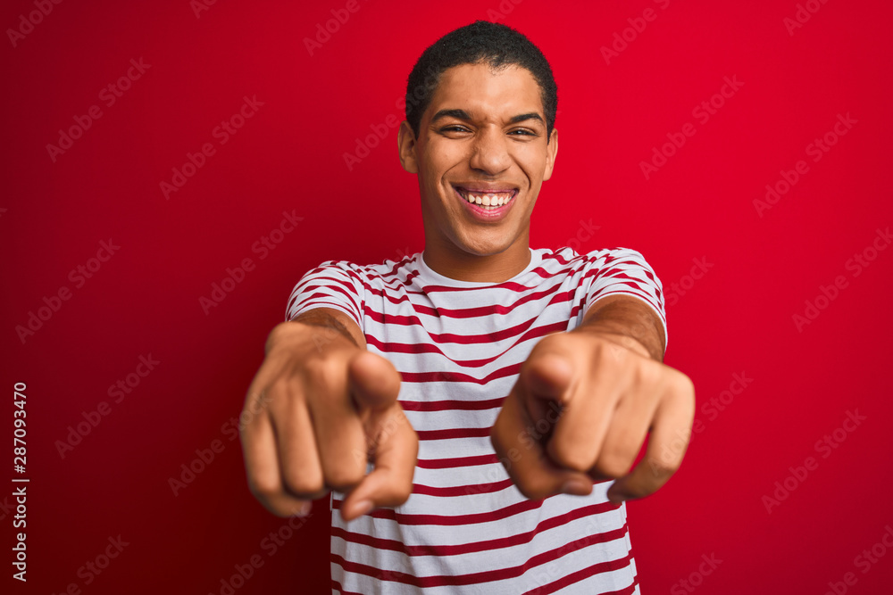 Fototapeta premium Young handsome arab man wearing striped t-shirt over isolated red background pointing to you and the camera with fingers, smiling positive and cheerful