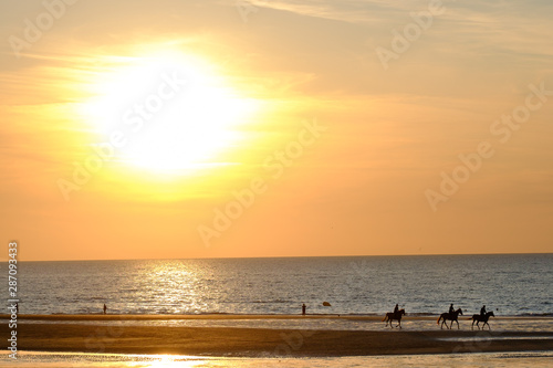 Fototapeta Naklejka Na Ścianę i Meble -  Normandy sunset with riders on the beach