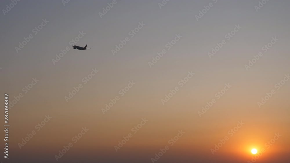 Aircraft is gaining altitude in the sky above the sun at sunset Aircraft is gaining altitude in the sky above the sun at sunset