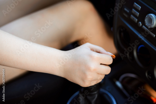Hand of the female driver of the car on the gear handle