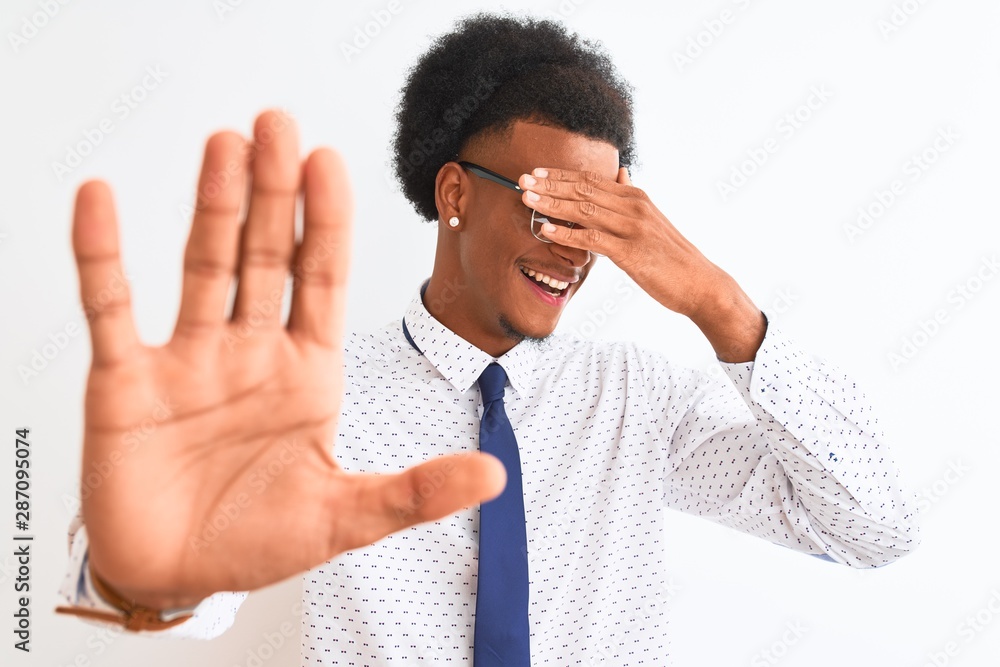 Young african american businessman wearing tie and glasses over isolated white background covering eyes with hands and doing stop gesture with sad and fear expression. Embarrassed Young african american businessman wearing tie and glasses over isolated white background covering eyes with hands and doing stop gesture with sad and fear expression. Embarrassed