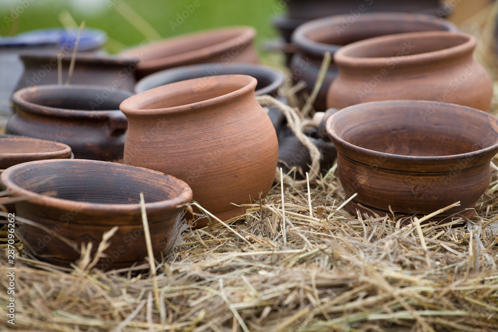 a large number of clay pots lies on a bale of hay