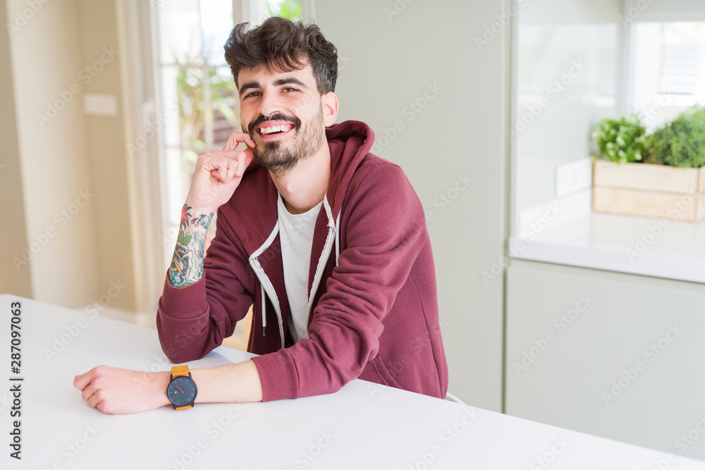 Handsome young man smiling cheerful at the camera with a big smile on face showing teeth Handsome young man smiling cheerful at the camera with a big smile on face showing teeth