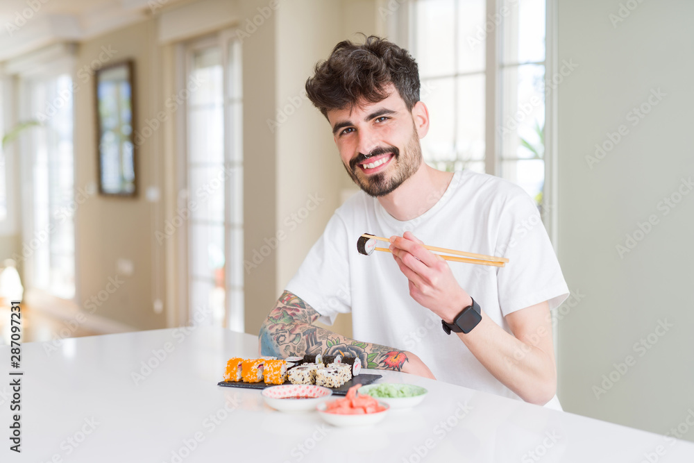 Young man eating sushi asian food using choopsticks Young man eating sushi asian food using choopsticks