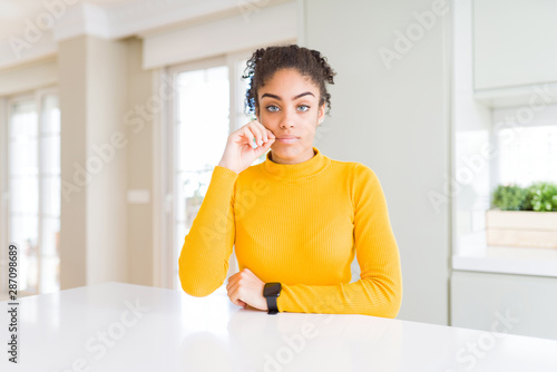Beautiful african american woman with afro hair wearing a casual yellow sweater mouth and lips shut as zip with fingers. Secret and silent  taboo talking