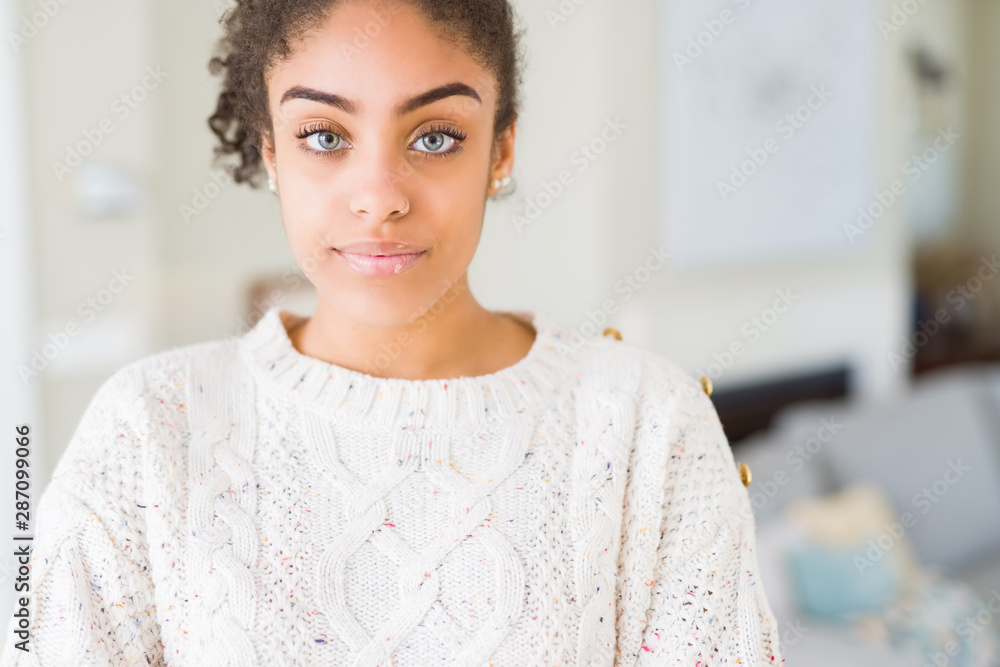 Beautiful young african american woman with afro hair wearing casual sweater Relaxed with serious expression on face. Simple and natural with crossed arms Beautiful young african american woman with afro hair wearing casual sweater Relaxed with serious expression on face. Simple and natural with crossed arms