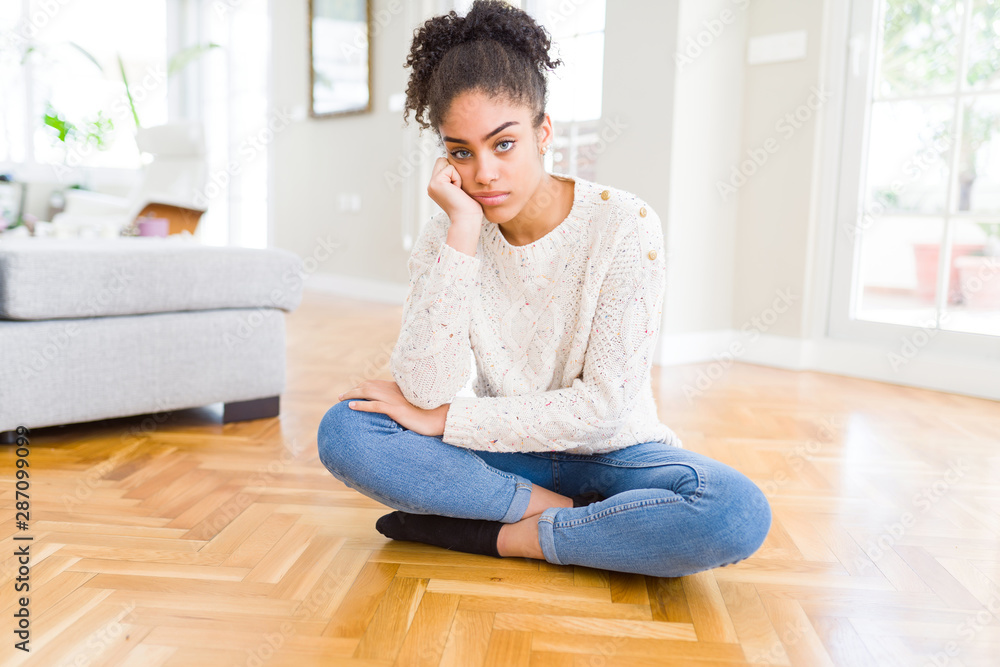Beautiful young african american woman with afro hair sitting on the floor thinking looking tired and bored with depression problems with crossed arms. Beautiful young african american woman with afro hair sitting on the floor thinking looking tired and bored with depression problems with crossed arms.