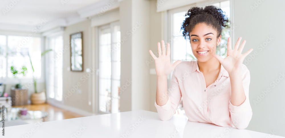 Wide angle of beautiful african american woman with afro hair showing and pointing up with fingers number ten while smiling confident and happy. Wide angle of beautiful african american woman with afro hair showing and pointing up with fingers number ten while smiling confident and happy.
