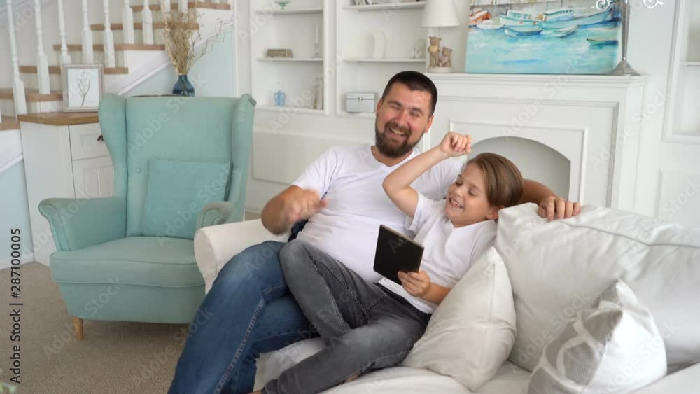 Father and his son using gadgets. Emotionally react to the game on the tablet