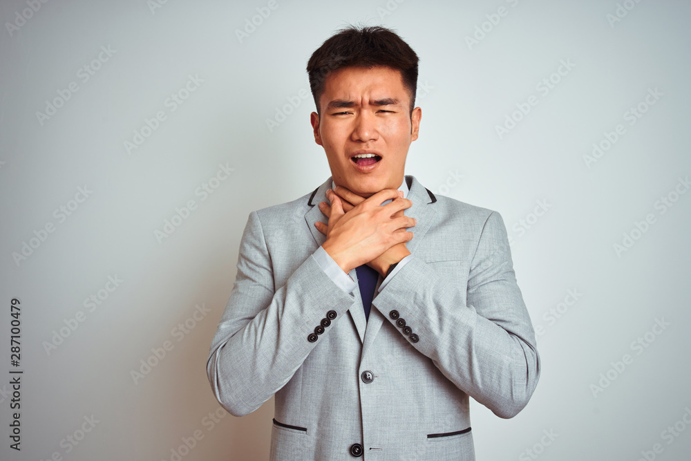 Asian chinese businessman wearing grey jacket and tie standing over isolated white background shouting and suffocate because painful strangle. Health problem. Asphyxiate and suicide concept. Asian chinese businessman wearing grey jacket and tie standing over isolated white background shouting and suffocate because painful strangle. Health problem. Asphyxiate and suicide concept.