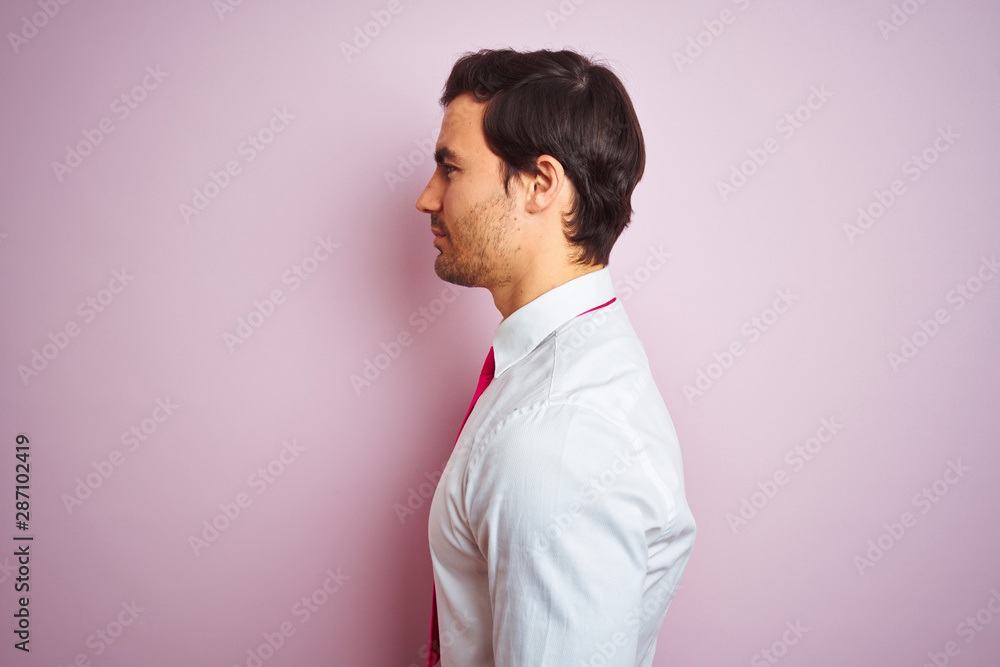 Young handsome businessman wearing shirt and tie standing over isolated pink background looking to side, relax profile pose with natural face with confident smile. Young handsome businessman wearing shirt and tie standing over isolated pink background looking to side, relax profile pose with natural face with confident smile.
