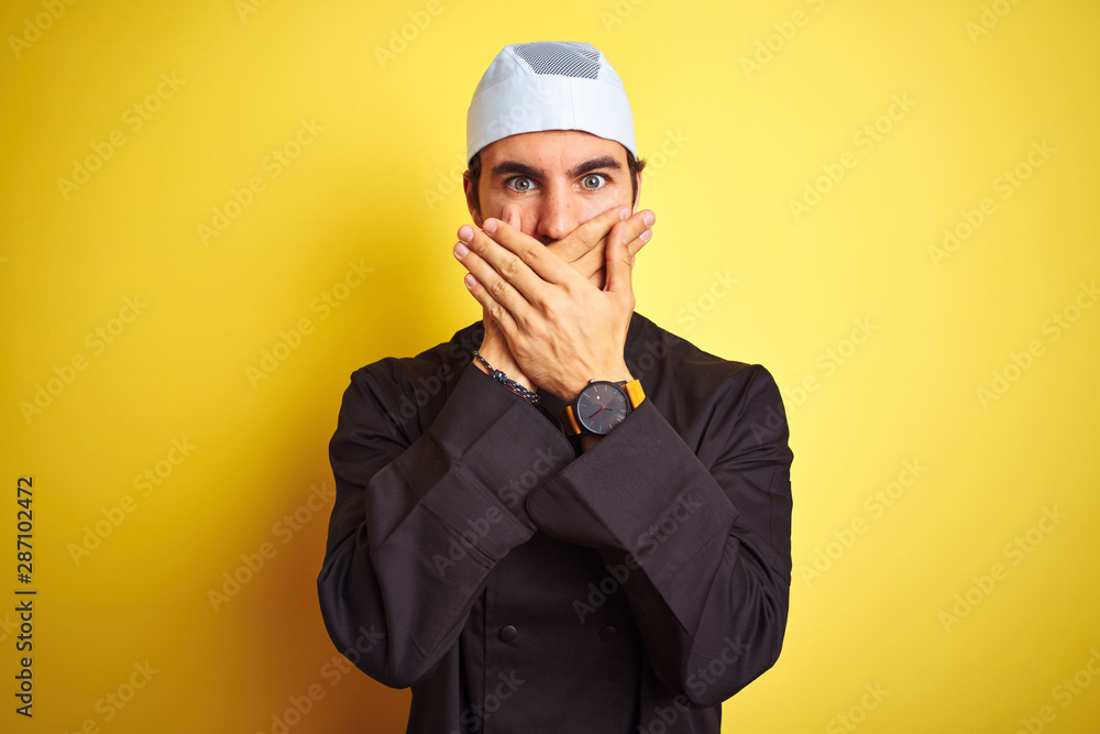 Young handsome chef man cooking wearing uniform and hat over isolated yellow background shocked covering mouth with hands for mistake. Secret concept. Young handsome chef man cooking wearing uniform and hat over isolated yellow background shocked covering mouth with hands for mistake. Secret concept.